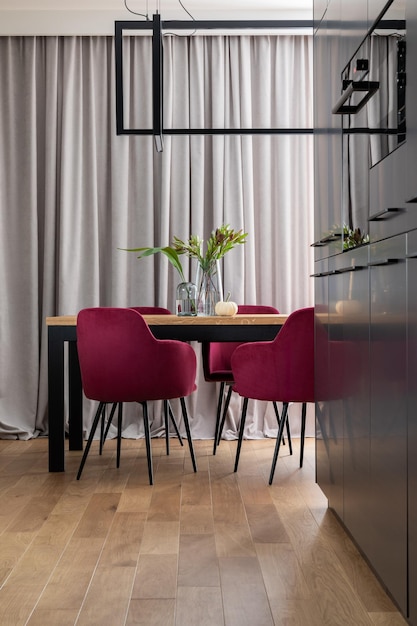 Stijlvolle compositie van keuken en eetkamer open ruimte interieur Minimalistische ergonomische keukenruimte Fluwelen stoelen houten tafel en persoonlijke accessoires in de moderne eetkamer Sjabloon