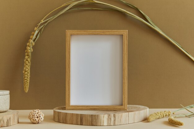 Stijlvolle compositie van minimalistisch kamerinterieur met mock-up posterframe, natuurlijke materialen als hout en marmer, droge planten en persoonlijke accessoires. Neutrale en gele kleuren, sjabloon.