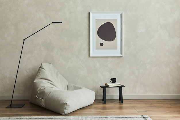 Stijlvolle compositie van minimalistisch woonkamerinterieur met mock-up posterframe, grijze poef en elegante persoonlijke accessoires. Neutrale muur, tapijt op de parketvloer. Sjabloon.