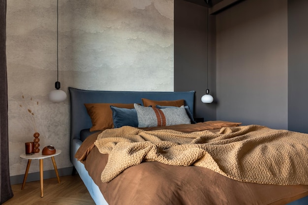 Stijlvolle compositie van modern slaapkamerinterieur Bed creatieve lamp en elegante persoonlijke accessoires Betonnen muur Bruine lakens Minimalistisch mannelijk concept Sjabloon