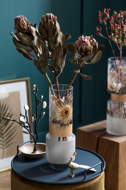 Stijlvolle en bloemige compositie van prachtige bloemen in moderne vaas op de fluwelen poef met elegante accessoires en meubels. Bloesemconcept bij woonkamer. Groene muren. Interieur ontwerp.
