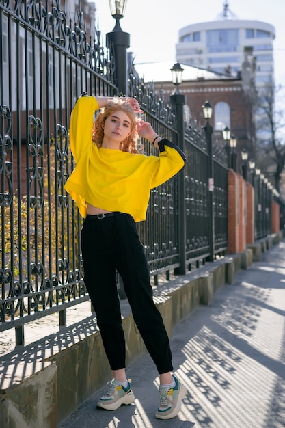 Stijlvolle gelukkige jonge vrouw in een fel geel sweatshirt