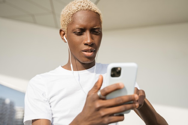 Foto stijlvolle glimlachende afro-amerikaanse man die mobiele telefoon gebruikt om online op straat te winkelen