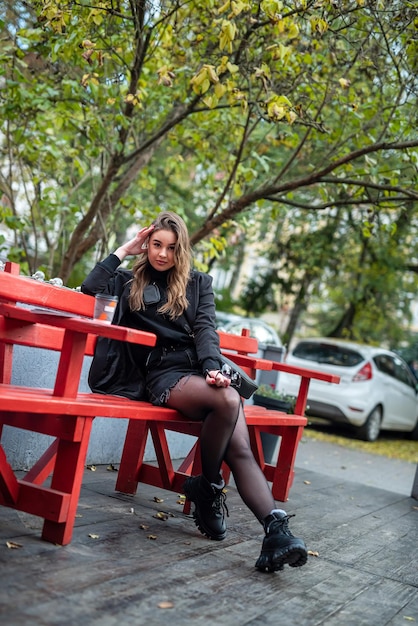 Stijlvolle goed verzorgde vrouw met een mooi gezicht en figuur loopt door de straten van de stad waar de herfst komt. Zwarte warme kleren op een jonge vrouw. Herfst concept. Stadsconcept. Het concept van koude.