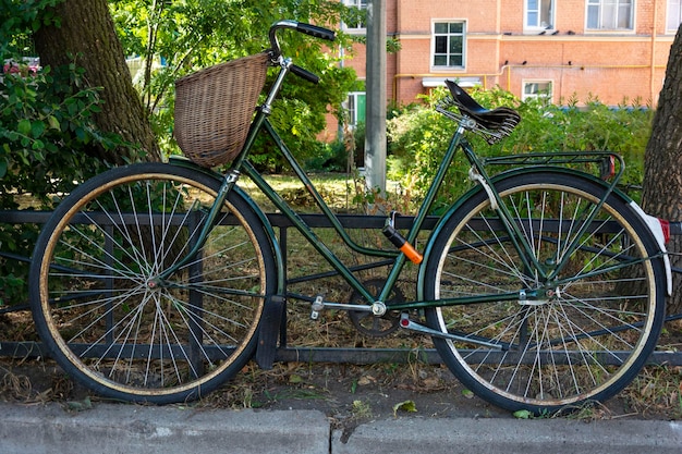 Foto stijlvolle groene vintage retro fiets met rieten mand geparkeerd in de stad