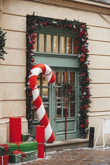 Stijlvolle grote zuurstok rood en groen verpakte kerstcadeaus dennentakken kransen op de buitenkant van het gebouw Modern kerstdecor in stadsstraat Wintervakantie in Europa