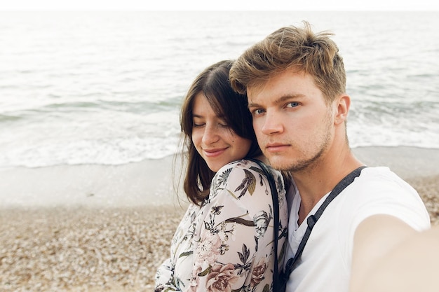 Stijlvolle hipster paar selfie te nemen en te omarmen op het strand in de avond Gelukkige familie ontspannen op huwelijksreis op zee Zomervakantie