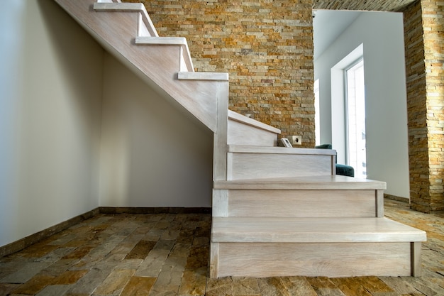 Stijlvolle houten eigentijdse trap in loft huis interieur. Moderne hal met decoratieve kalkstenen muren en witte eiken trappen.