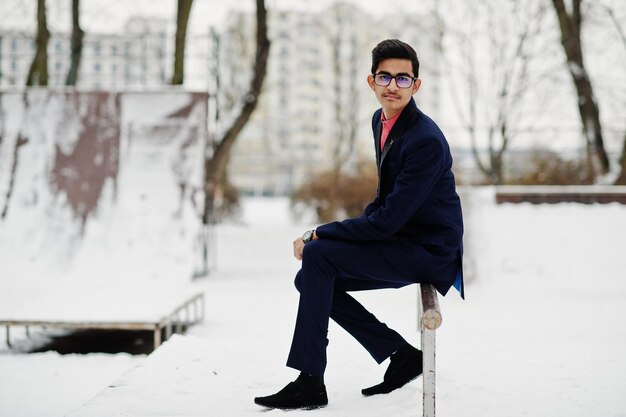 Stijlvolle indiase student man in pak en bril poseerde op winterdag buiten