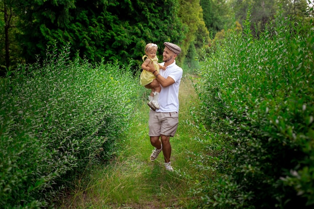 Stijlvolle jonge blanke vader loopt met dochtertje in de tuin