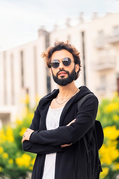 Stijlvolle jonge man met gekruiste armen buitenshuis