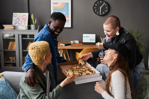 Foto stijlvolle jonge mensen praten en eten pizza.