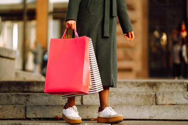 Stijlvolle jonge vrouw in trendy kleding met boodschappentassen na het winkelen Herfst winkelen