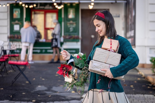 Stijlvolle jonge vrouw met kerstcadeaus buitenshuis