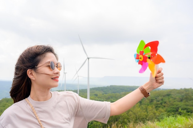 Stijlvolle jonge vrouw toerist in een windmolen bij het opwekkingsstation voor hernieuwbare energie De achtergrond is een prachtige bergwindmolen