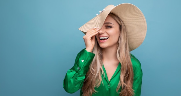 Stijlvolle jonge vrouw toerist op vakantie in een zomer stro hoed op een blauwe studio achtergrond