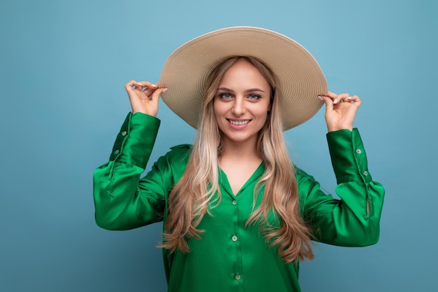 Stijlvolle jonge vrouw toerist op vakantie in een zomer stro hoed op een blauwe studio achtergrond