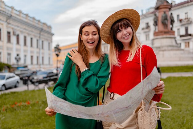 Stijlvolle jonge vrouwen die samen reizen in Europa, gekleed in trendy lente-outfit en accessoires met kaart