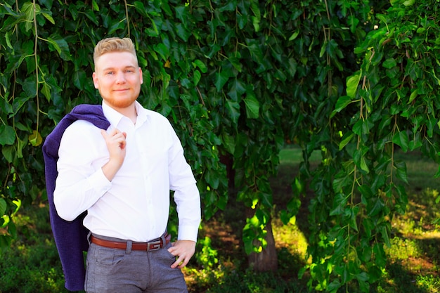 Stijlvolle jonge zelfbewuste man in pak in het zomerpark. Jonge zakenman portret.