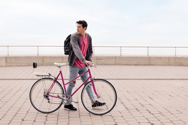 Stijlvolle jongeman die loopt met een vintage fietsconcept van duurzaam transport