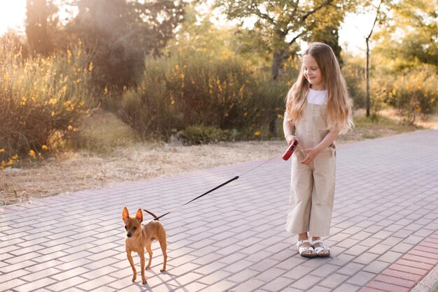 Stijlvolle jongen meisje lopen in park met binnenlandse hond buitenshuis