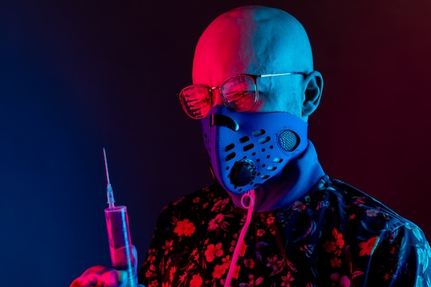 Stijlvolle kale man met medische masker met bril en spuit met vaccin te houden