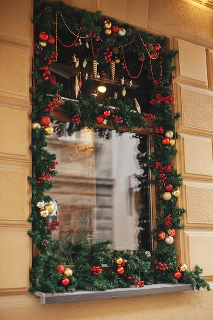 Stijlvolle kerstboog met rode en gouden kerstballen hangend aan dennentakken aan de buitenkant van het gebouw Modern kerstdecor in stadsstraat Wintervakantie in Europa Vrolijk kerstfeest