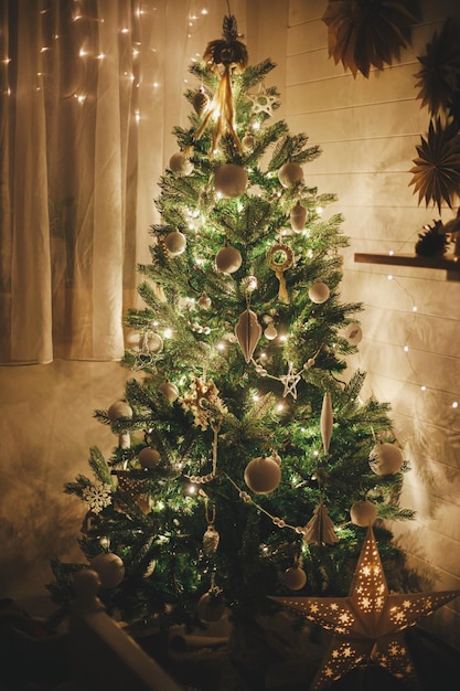 Stijlvolle kerstboom met witte kerstballen, boho-ornamenten en gouden lichtjes in de vooravond van de magische tijd