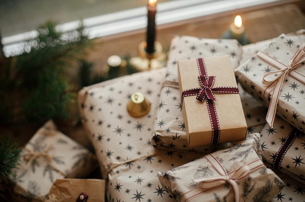 Stijlvolle kerstcadeaus verpakt in ambachtelijk papier vintage kaarsen sparren takken op rustiek hout