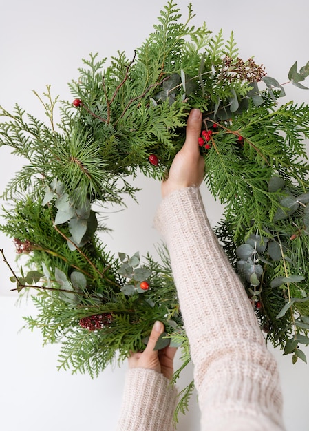 Stijlvolle kerstkrans voor het interieur hang de krans aan de deur Handgemaakt het meisje houdt een vers gemaakte krans in haar handen De sfeer van de vakantie Kerstmis en Nieuwjaar