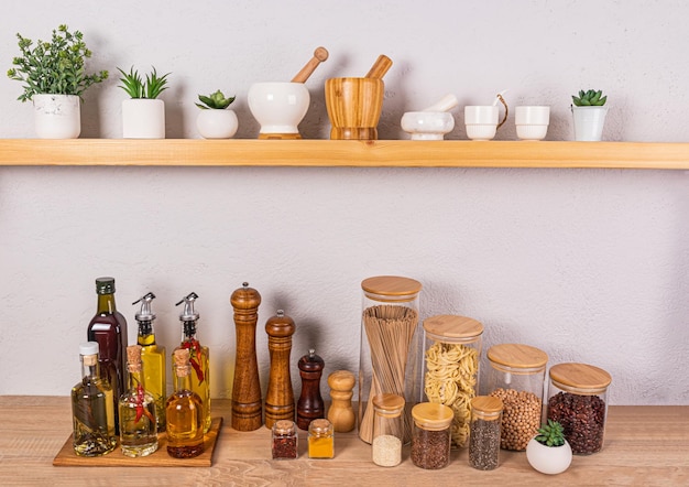 Stijlvolle keuken achtergrond met een set flessen met verschillende kookoliën glazen potten met specerijen Voorbeeld van een open houten plank
