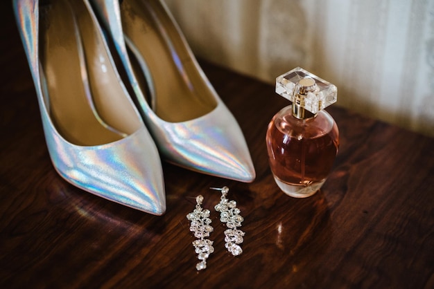 Stijlvolle klassieke gelakte zilveren schoenen parfum een oorbel op houten achtergrond Close-up bovenaanzicht