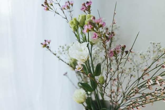 Stijlvolle lentebloemen eustoma gypsophila en chamelaucium op achtergrond van rustieke muur Bloemengroeten Fijne vrouwendag en moederdag Modern boeket