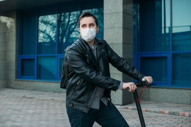 Stijlvolle man met beschermend masker elektrische scooter rijden