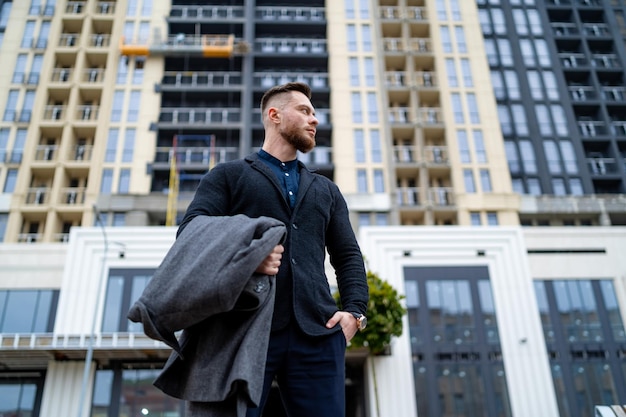 Stijlvolle man staande op stedelijke straat Portret van knappe jonge man poseren voor camera