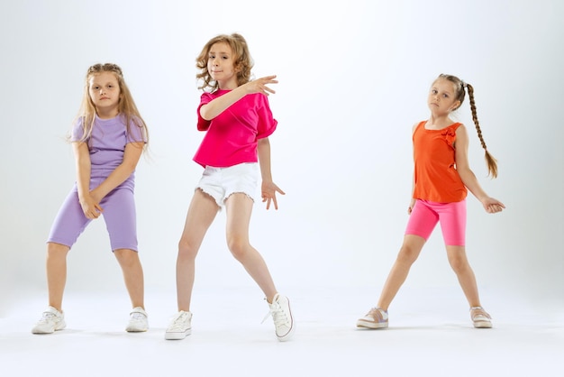 Stijlvolle mooie meisjes kinderen dansen opleiding plezier geïsoleerd over witte studio achtergrond