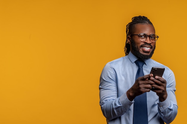 Stijlvolle ondernemer met de smartphone bij de muur