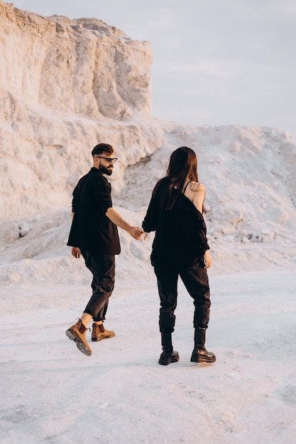 Stijlvolle paar wandelen en knuffelen wandelen op een achtergrond van witte bergen Mooie hipster paar genieten van tijd samen Het concept van jeugd liefde en lifestyle lente