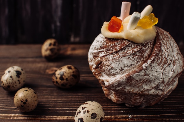 Stijlvolle Pasen cake met marshmallows en jelly bears op donkere rustieke houten achtergrond, kwarteleitjes liggen in de buurt. Seizoensgebonden groeten Vrolijk Pasen. Modern vrolijk Pasen-beeld