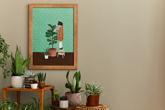 Stijlvolle plantkundesamenstelling van huistuininterieur met houten mock-up posterframe, gevuld met veel mooie kamerplanten, cactussen, vetplanten in verschillende designpotten en bloemenaccessoires