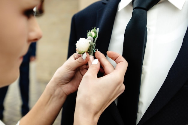 Foto stijlvolle prachtige bruid corsages aantrekken op elegante bruidegom tijdens kerkceremonie