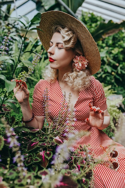 Stijlvolle retro en vintage vrouw in tuin vol tropische planten en bloemen