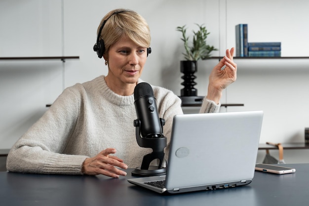 Stijlvolle rijpe vrouw neemt een audiopodcast op in haar gezellige appartement