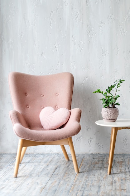 Foto stijlvolle roze fauteuil met hartvormig kussen in een helder minimalistisch interieur