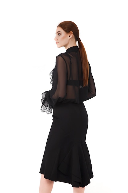 Stijlvolle schattige jonge zakenvrouw in zwarte elegante blouse en hoed op witte geïsoleerde muur. Vrouw in modieuze kleding poseren. Concept van stijl, mode,