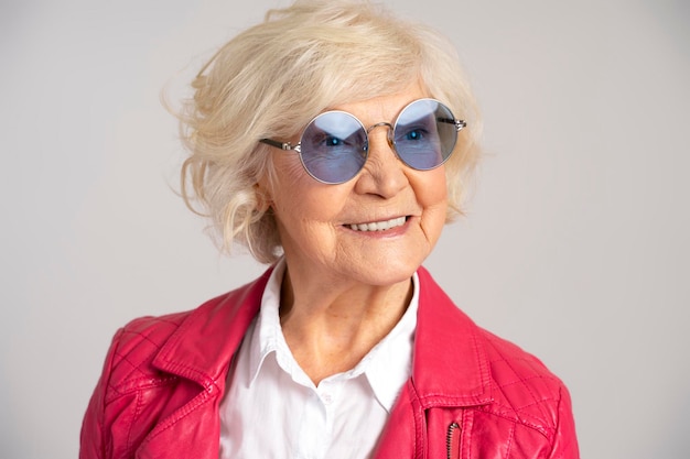 Stijlvolle senior lachende blanke vrouw met een bril die wegkijkt