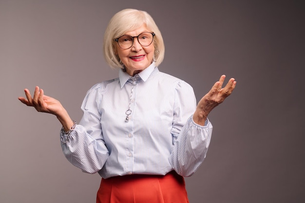 Stijlvolle senior vrouw in witte blouse ziet er zelfverzekerd uit