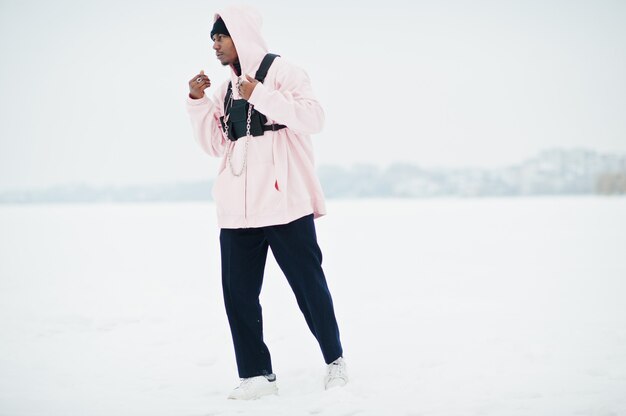 Stijlvolle stedelijke stijl Afro-Amerikaanse man in roze hoodie gesteld op bevroren meer in de winter.