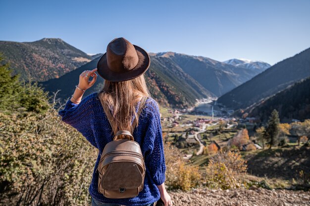 Stijlvolle trendy gratis hipster vrouw reiziger in een bruine hoed met rugzak op de bergen en uzungol meer in trabzon tijdens turkije reizen