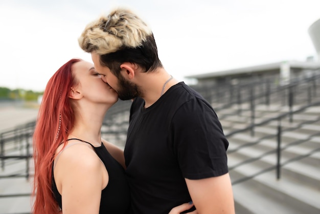 Stijlvolle verliefde paar in zwarte kleding wandelingen in het park en knuffels mooie paar hipsters knuffelen en zoenen op de achtergrond van de trap jeugdliefde en lifestyle concept